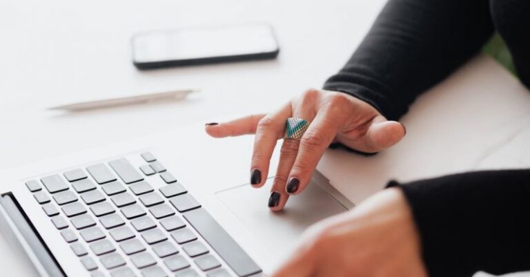 Strategies - Crop female using touchpad on laptop in office