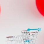 Ratio - A Miniature Shopping Cart Against Red Balloons on White Background