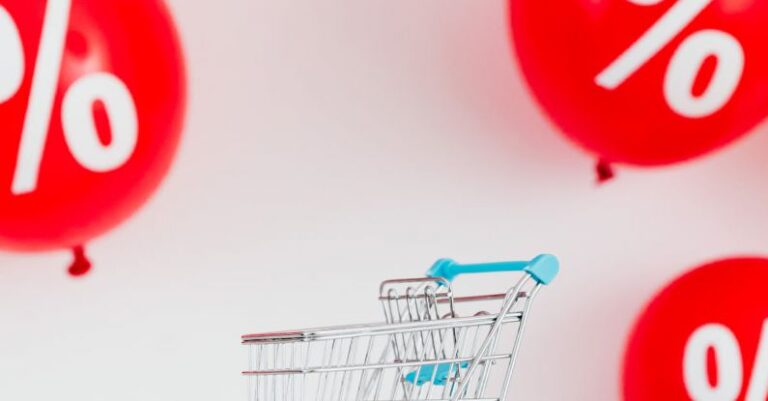 Ratio - A Miniature Shopping Cart Against Red Balloons on White Background