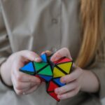 Opportunities - Crop anonymous girl demonstrating and solving colorful puzzle with triangles in soft focus