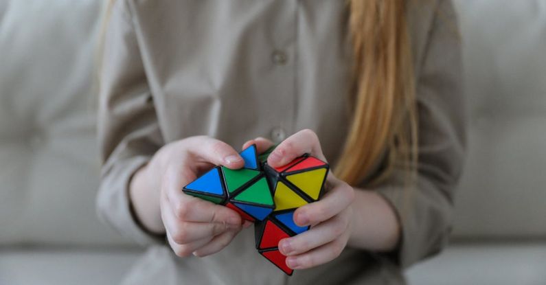 Opportunities - Crop anonymous girl demonstrating and solving colorful puzzle with triangles in soft focus