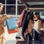 Acquisitions - Young woman demonstrating shopping bags to friends