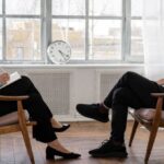 Fundamental Analysis - Person in Black Pants and Black Shoes Sitting on Brown Wooden Chair